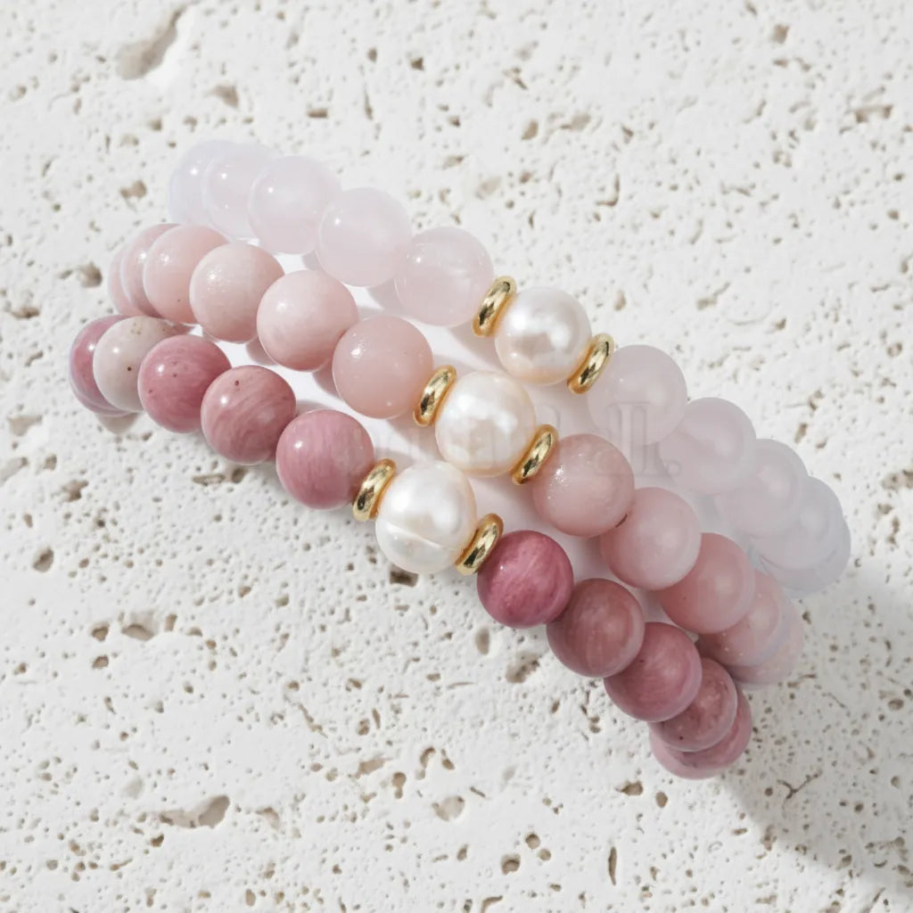 Set of pink and white beaded bracelets on a white cup with a light blue background