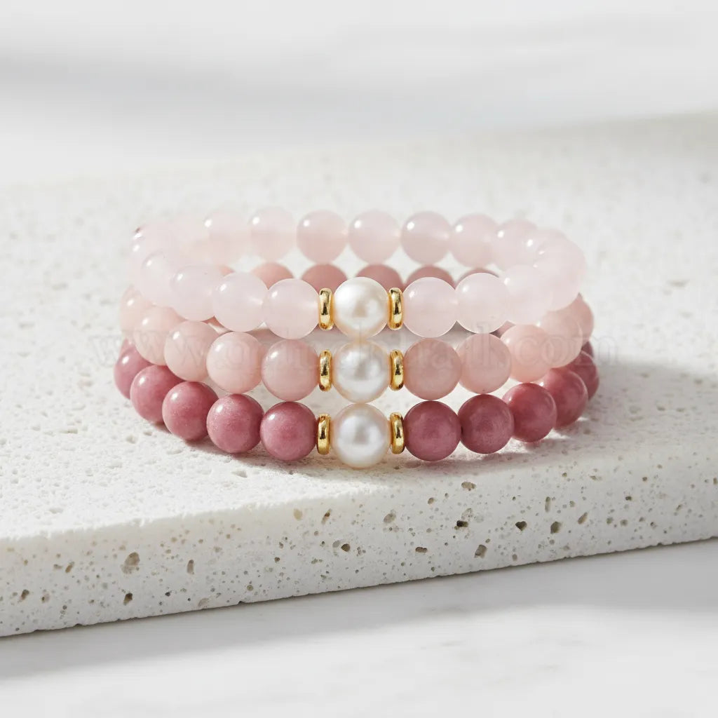 Set of pink beaded bracelets with gold accents on a white background