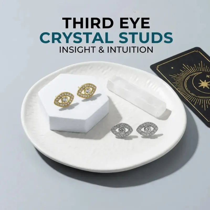Earrings on a white plate with a card labeled 'Third Eye Crystal Studs' on a gray background