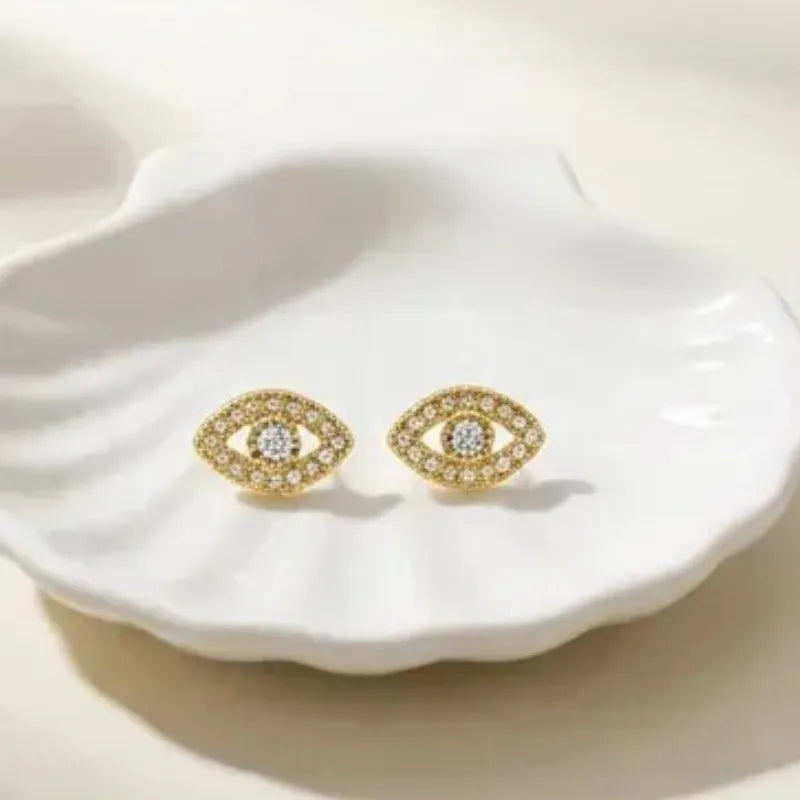 Gold earrings with gemstones on a white shell