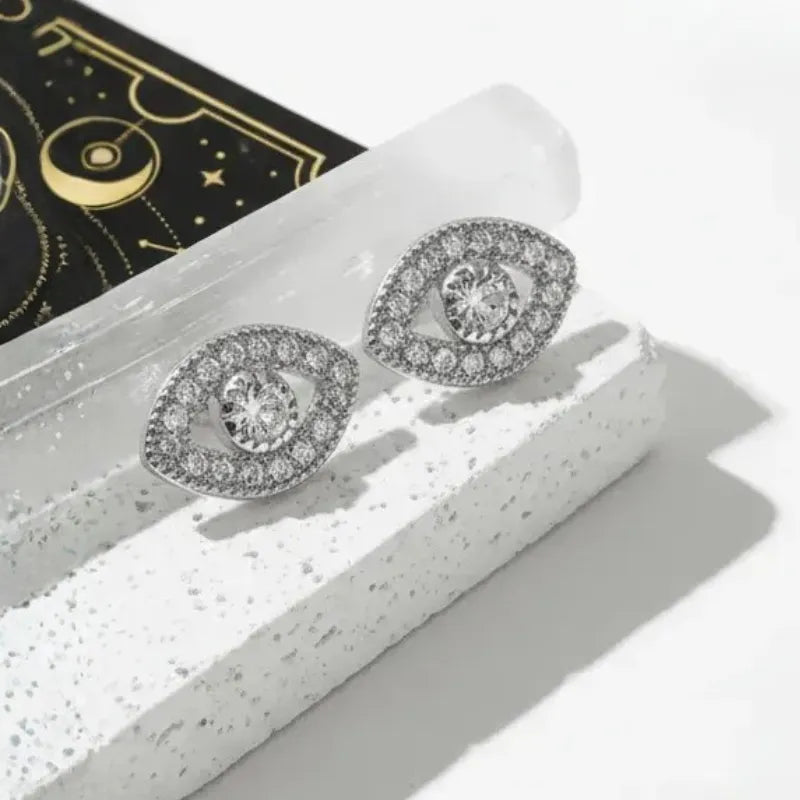Silver earrings with clear stones on a textured white surface