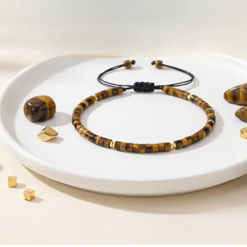 Tiger eye beaded bracelet on a white plate with scattered beads on a beige background