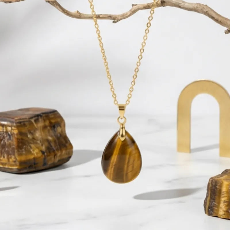 Gold necklace with a teardrop-shaped tiger's eye pendant on a white background