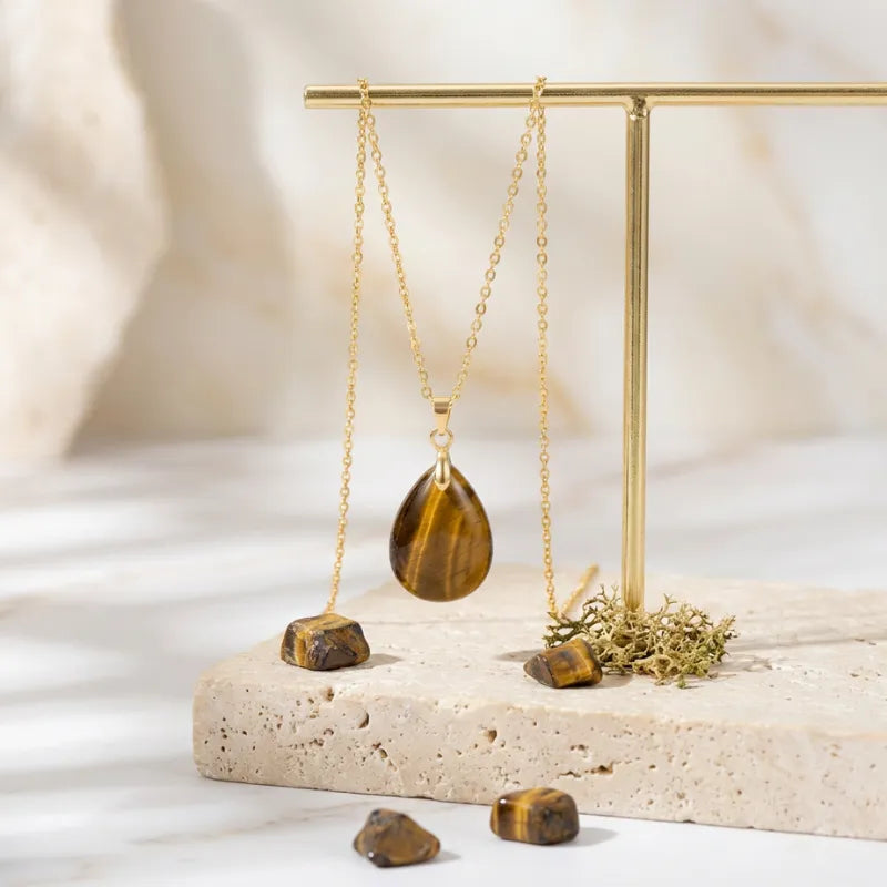 Jewelry set with gold chain necklace and pendant on a stone surface