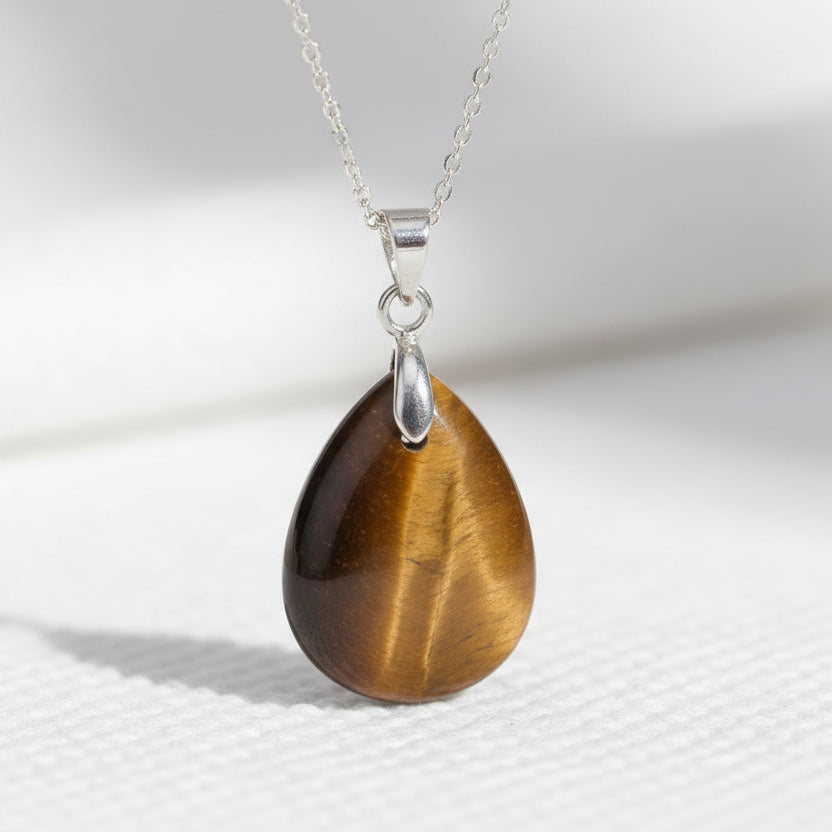 Teardrop-shaped brown pendant on a silver chain against a white background