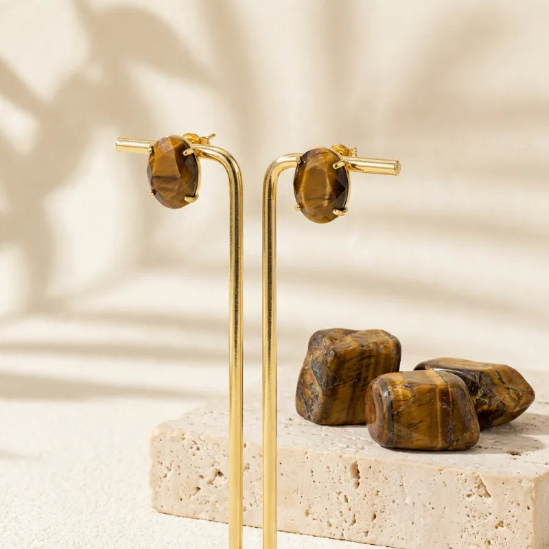 Gold hoop earrings with tiger's eye stones on a neutral background