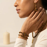 Woman wearing gold tiger eye earrings and bracelets — solar plexus chakra jewelry for confidence