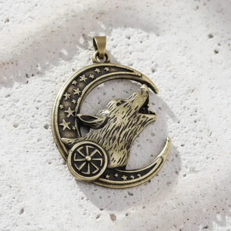 Bronze pendant with a wolf howling at the moon on a textured white surface