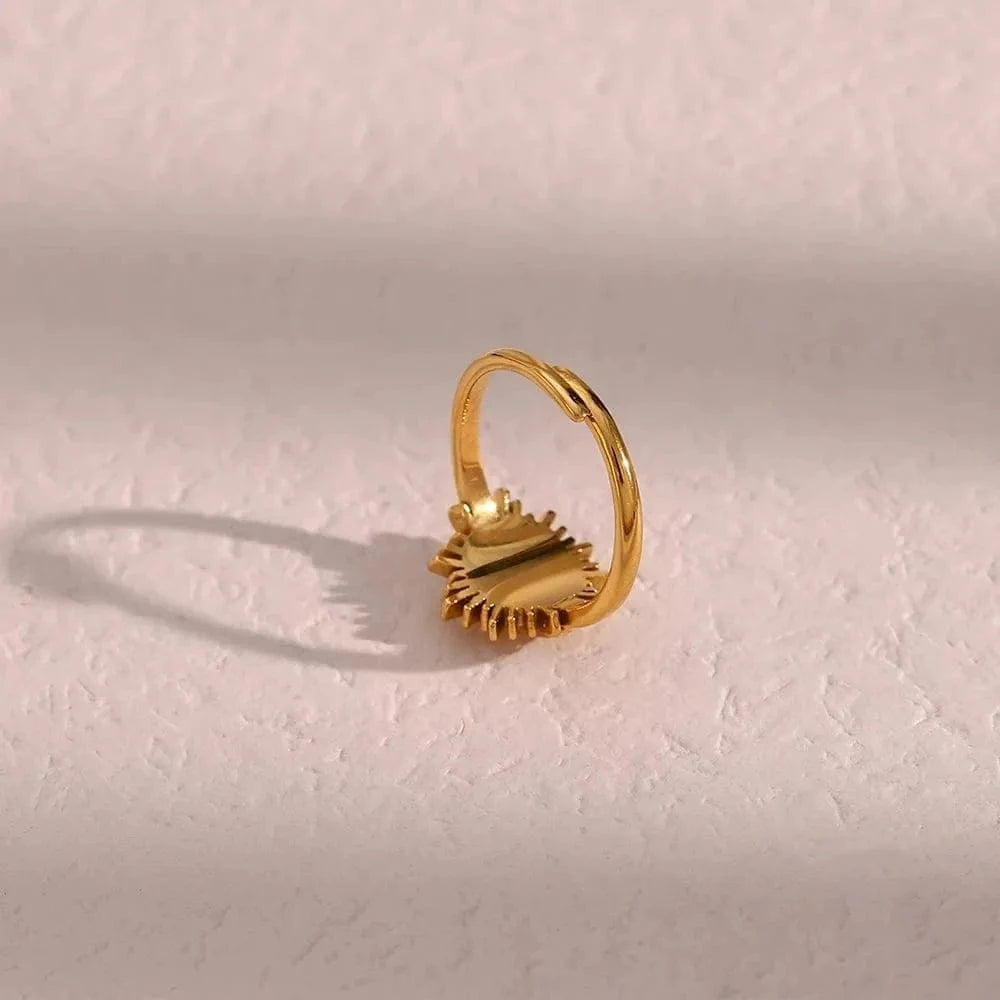 Gold ring with a textured design on a light pink background