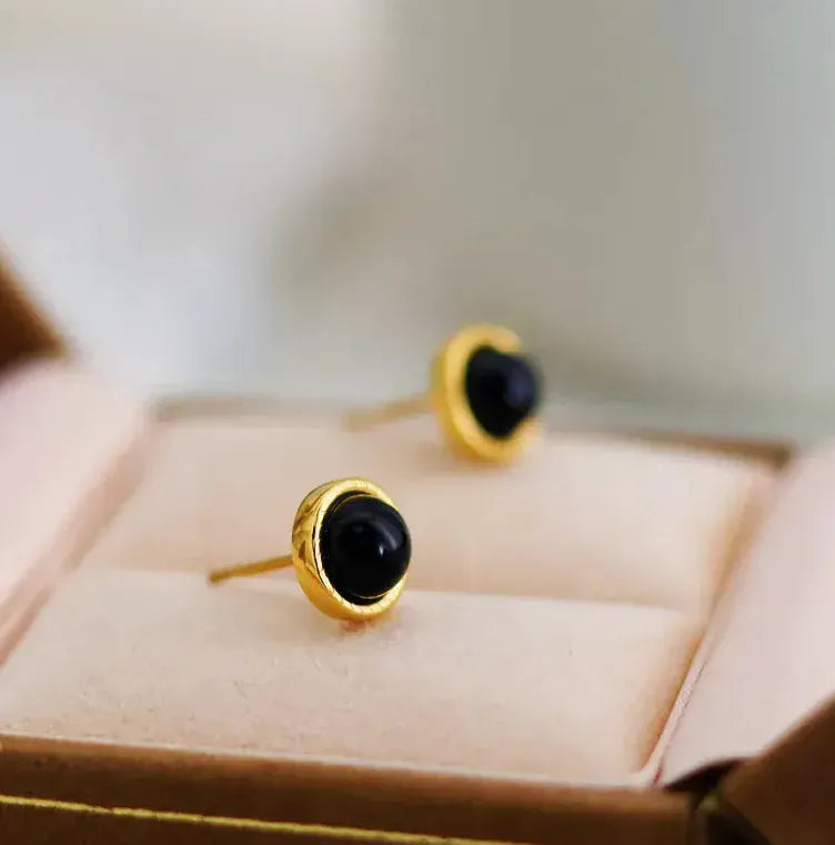Gold earrings with black stones on a jewelry box