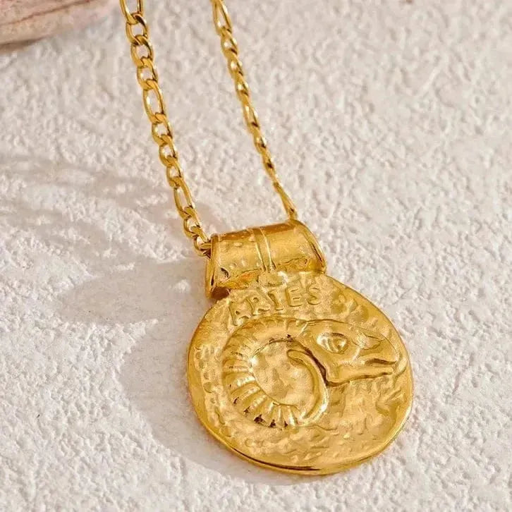 Gold necklace with a zodiac pendant on a textured beige background