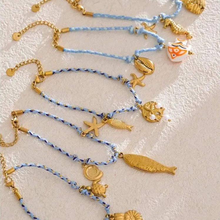 Set of gold charm bracelets on a textured white surface