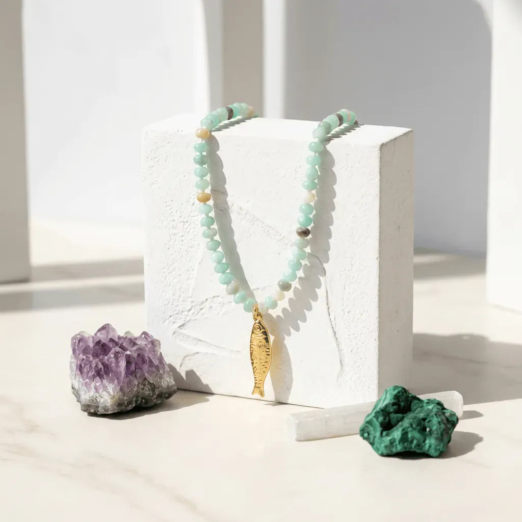 Necklace with a gold pendant on a white block, surrounded by crystals on a light background