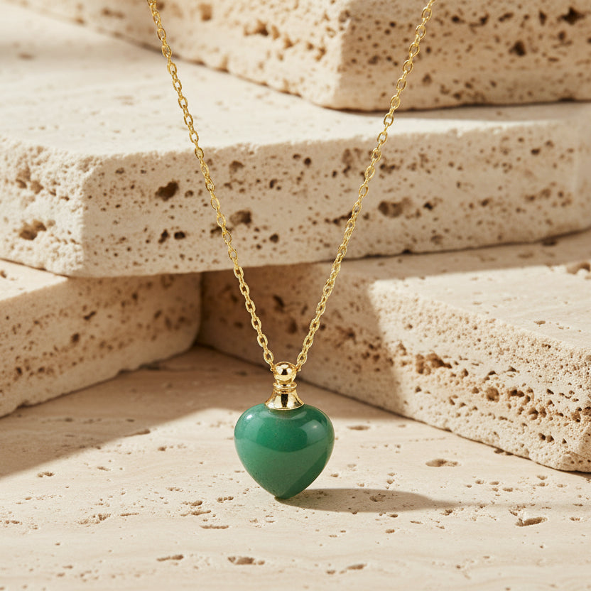 Gold necklace with a green heart-shaped pendant on a white background