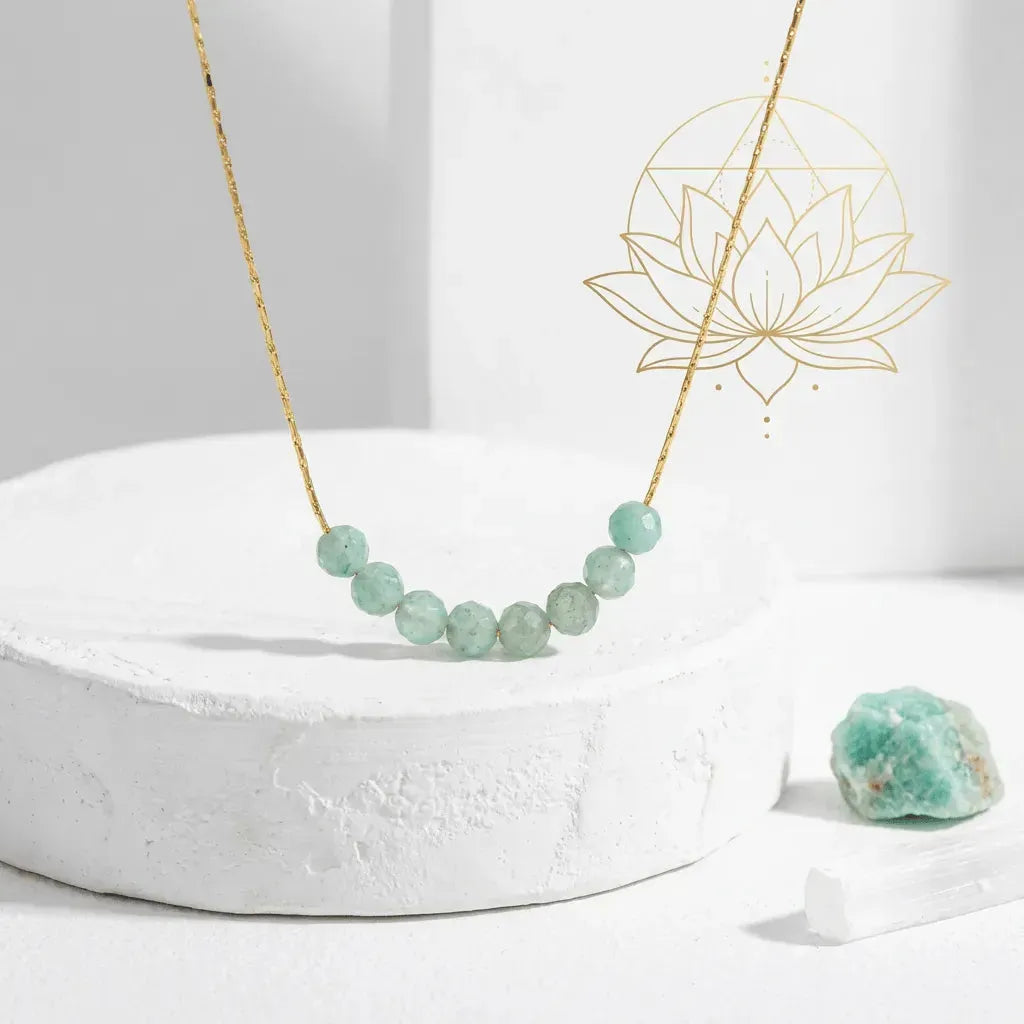 Necklace with green beads on a white surface with a decorative lotus flower in the background