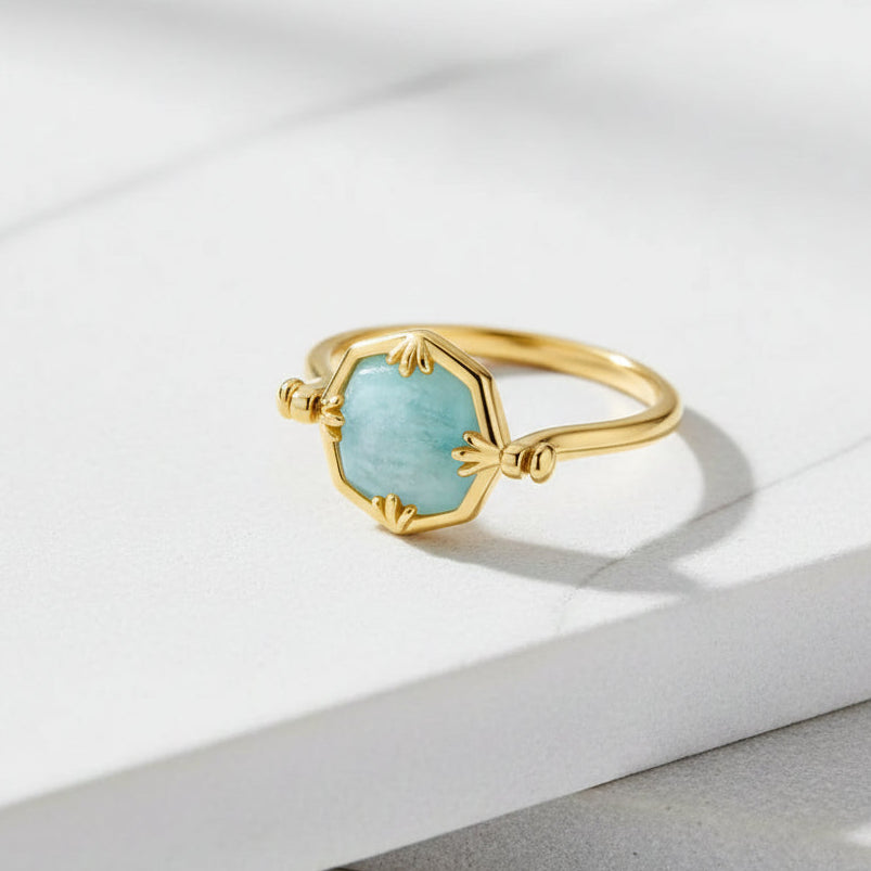 Gold ring with a light blue gemstone on a white background