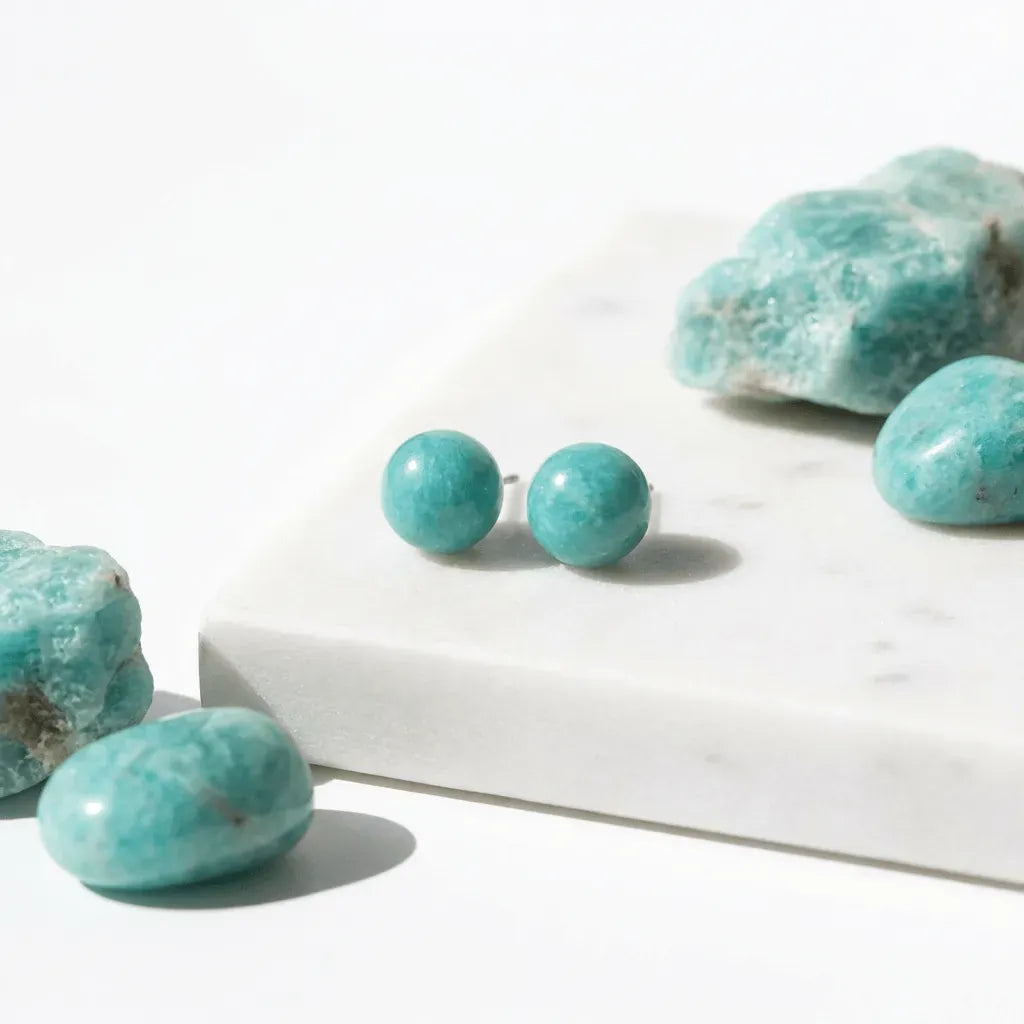 Turquoise stone earrings on a white surface with raw turquoise stones.