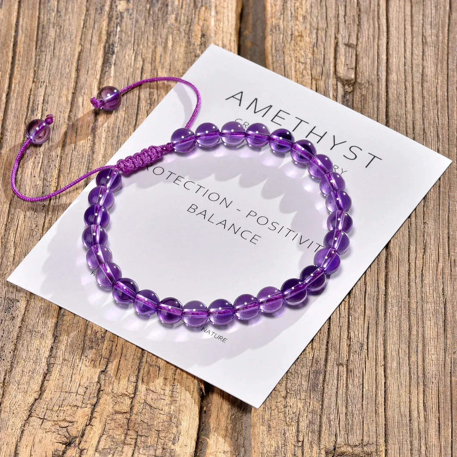 Amethyst bracelet on a card with text on a wooden surface
