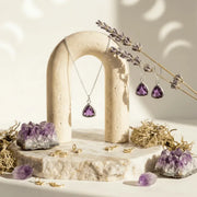 Jewelry display with purple gemstone necklace and earrings on a natural stone stand.