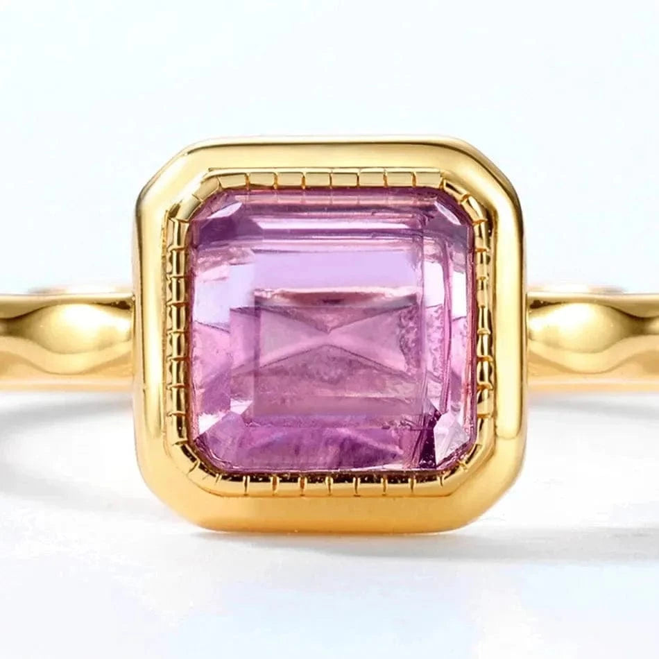 Gold ring with a pink gemstone on a white background