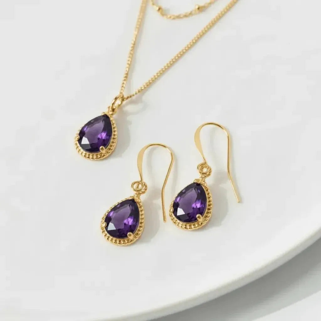 Gold jewelry set with purple gemstones on a white plate