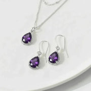 Purple teardrop jewelry set with silver accents on a white plate