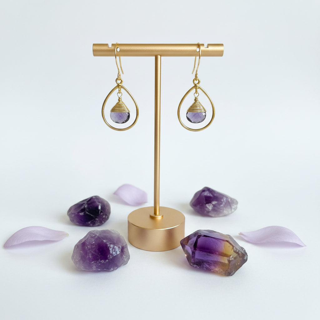 Close-up of gold fine hoop earring with wire-wrapped faceted amethyst drop