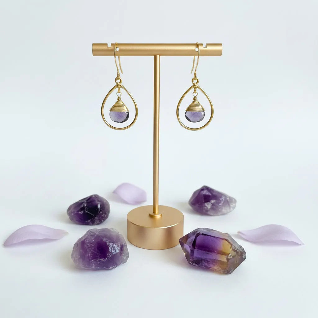 Close-up of gold fine hoop earring with wire-wrapped faceted amethyst drop