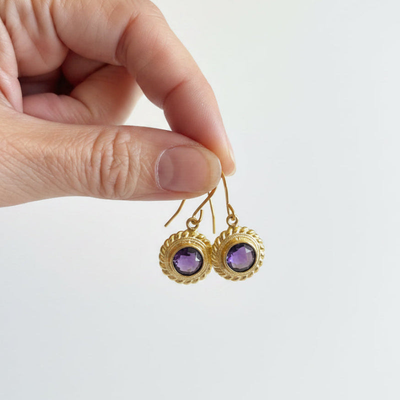 Amethyst Halo drop earrings held in hand to show scale