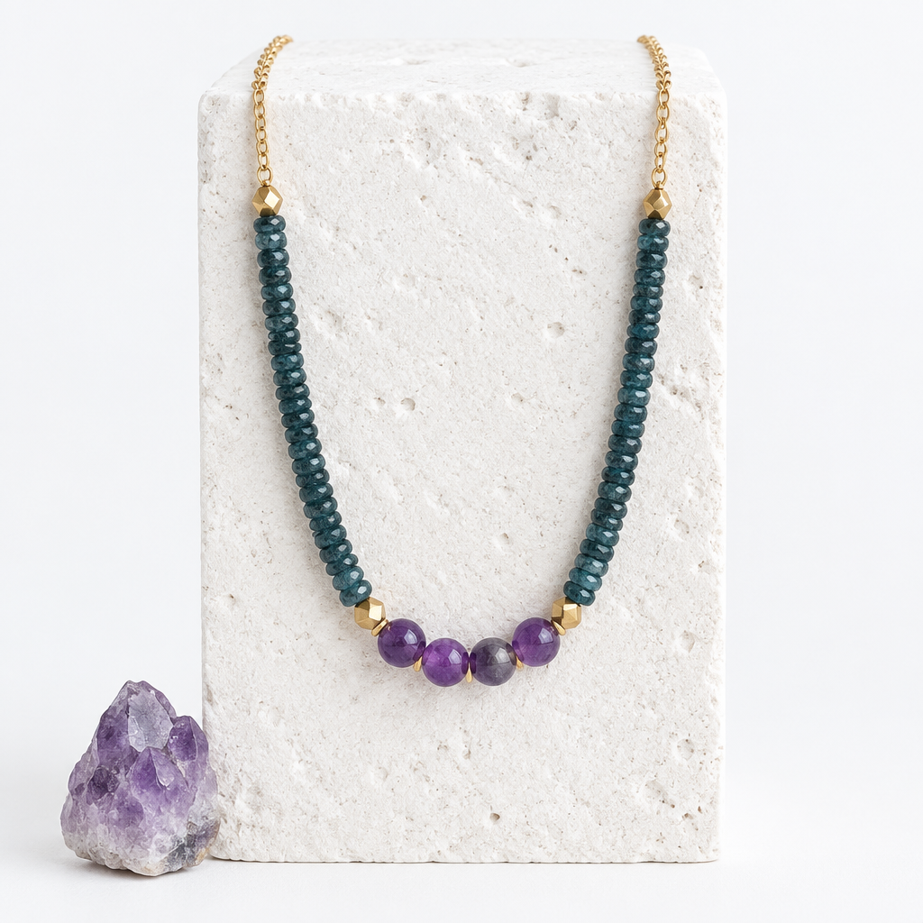 Amethyst and teal kyanite beaded necklace hanging on a white stone block beside an amethyst cluster