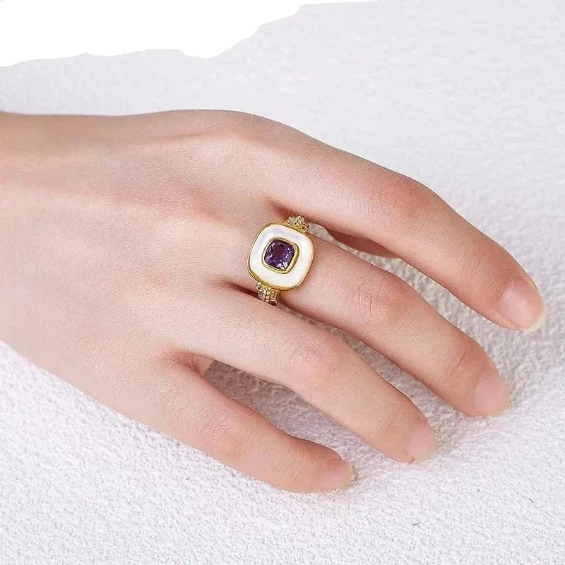 Gold ring with a purple gemstone on a hand