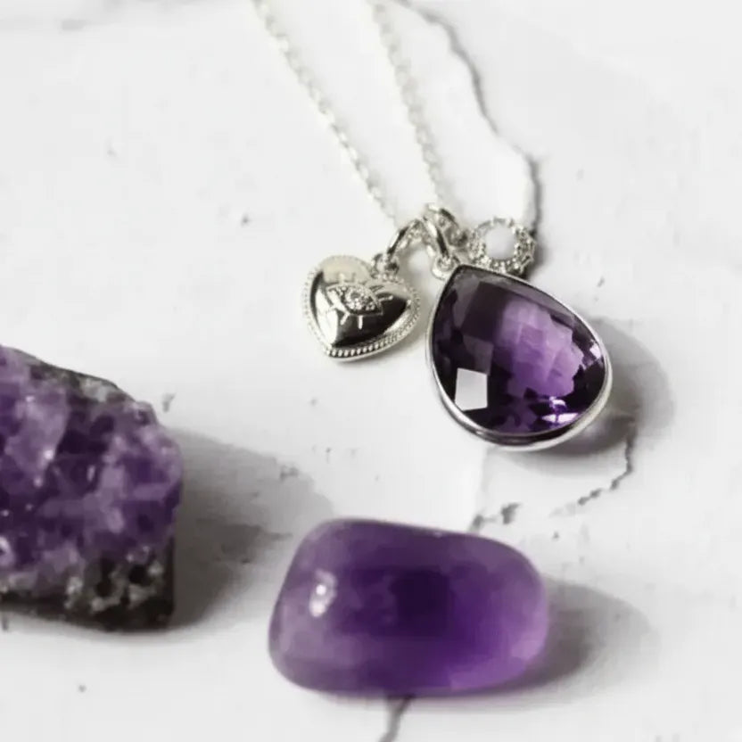 Necklace with purple teardrop pendant and heart charm on a white background