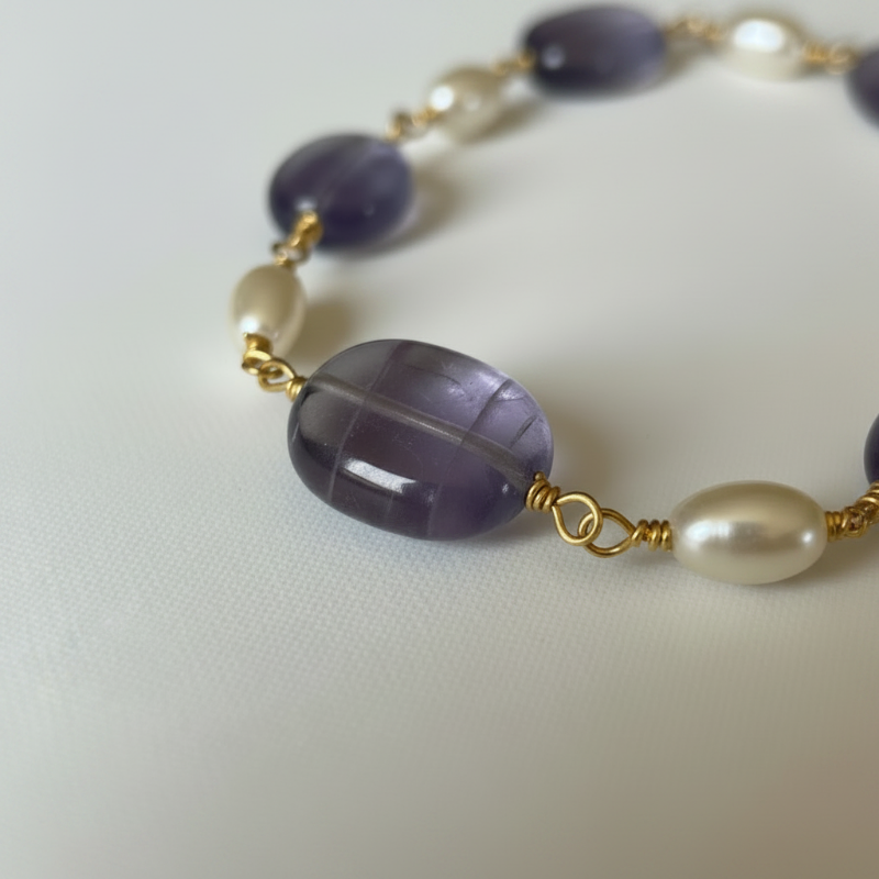 Close up of hand-wrapped amethyst ovals and freshwater pearls on gold links
