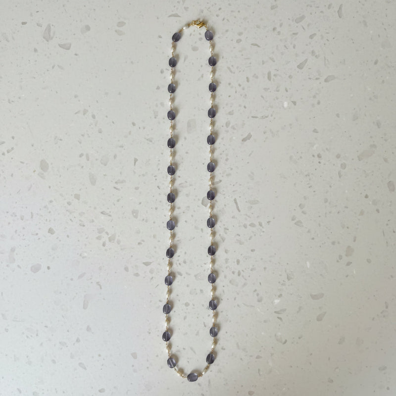 Full view of hand-wrapped amethyst and freshwater pearl long layering necklace on gold