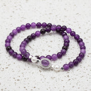 Purple beaded bracelet with a silver clasp on a white background