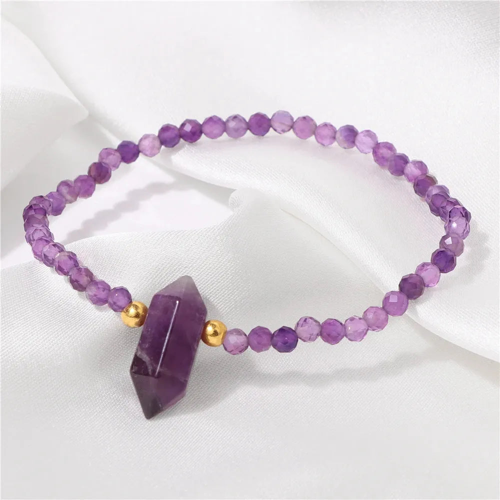 Purple beaded bracelet with a crystal point on a white fabric background