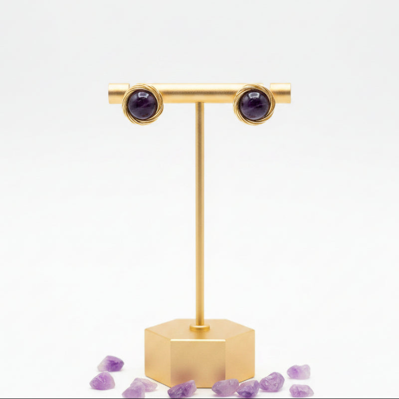 Close-up of a faceted genuine amethyst round stud earring in gold
