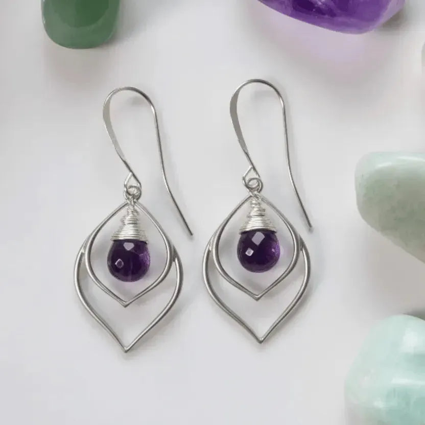 Silver earrings with purple gemstones on a light background