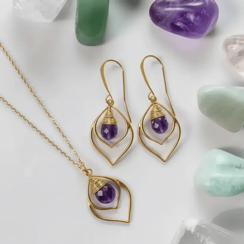 Gold jewelry set with purple gemstones on a light background