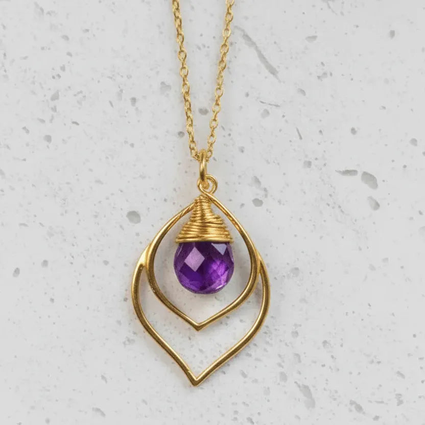 Gold necklace with a purple gemstone pendant on a light gray background