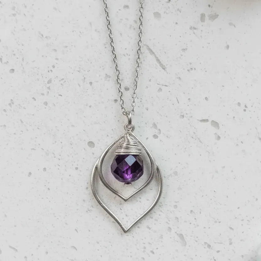 Silver necklace with a purple gemstone pendant on a light gray background
