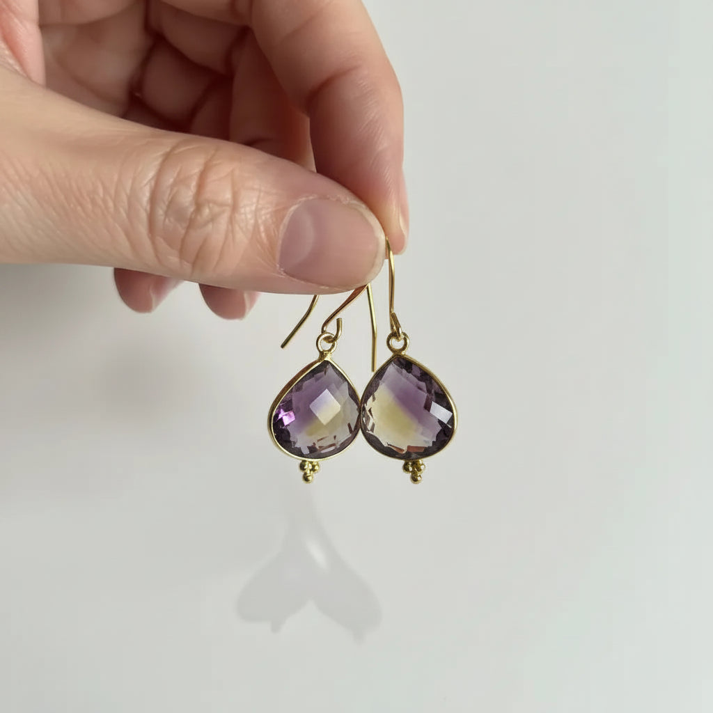 Gold ametrine drop earrings held in hand to show scale