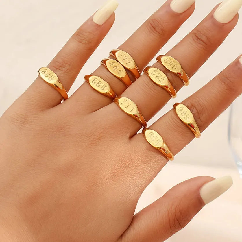 Hand wearing multiple gold rings with a blurred background