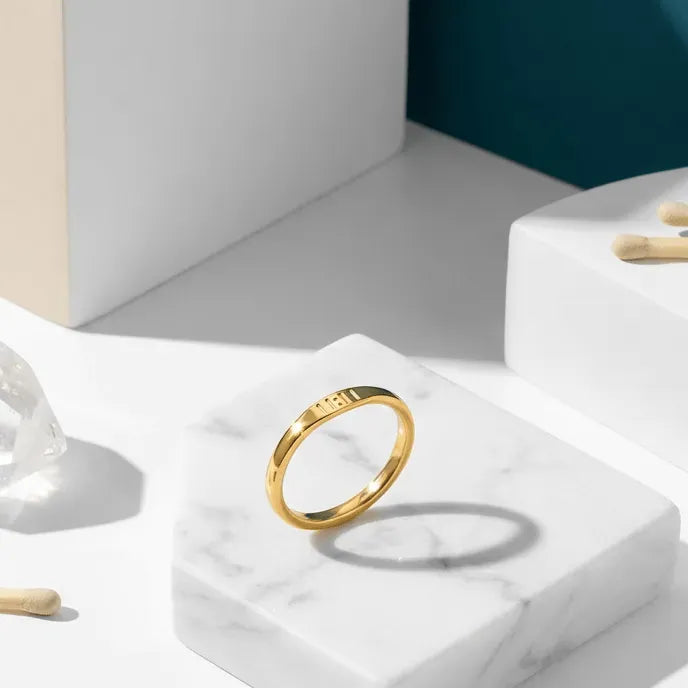 Gold ring on a white marble stand with tarot cards and wooden sticks, promotional text for '11:11 Ring'.