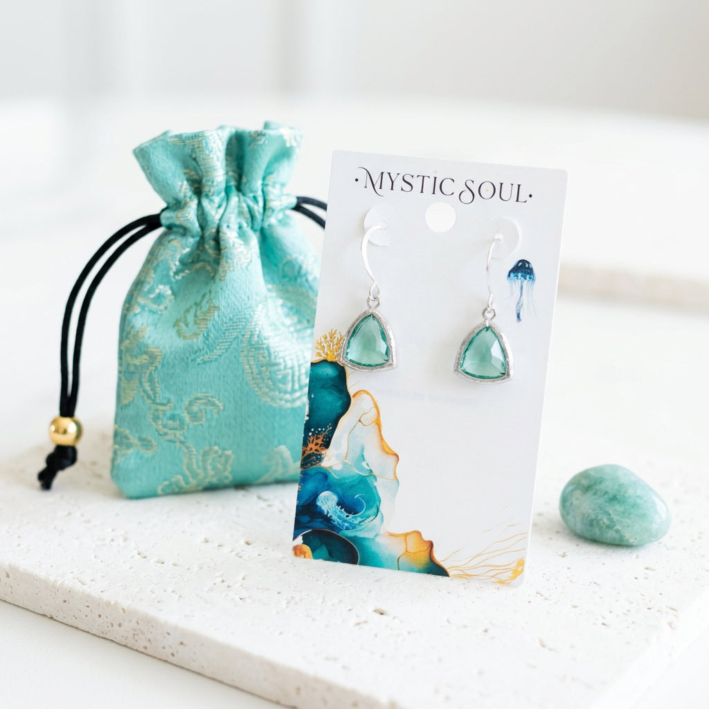 Silver Aqua Athena earrings with ocean blue faceted glass drops, shown with gift tag and pouch, March birthstone colour