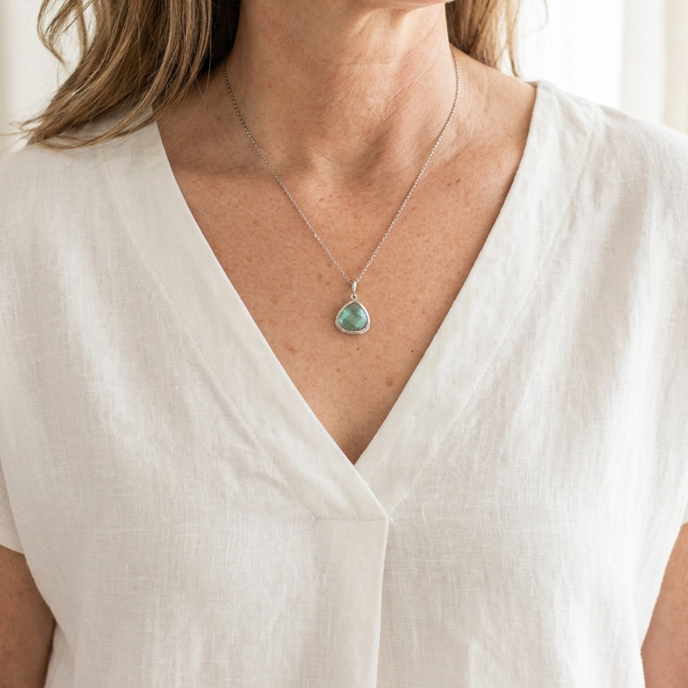 Woman wearing a silver Mini Pebble necklace with a small aqua blue faceted glass drop