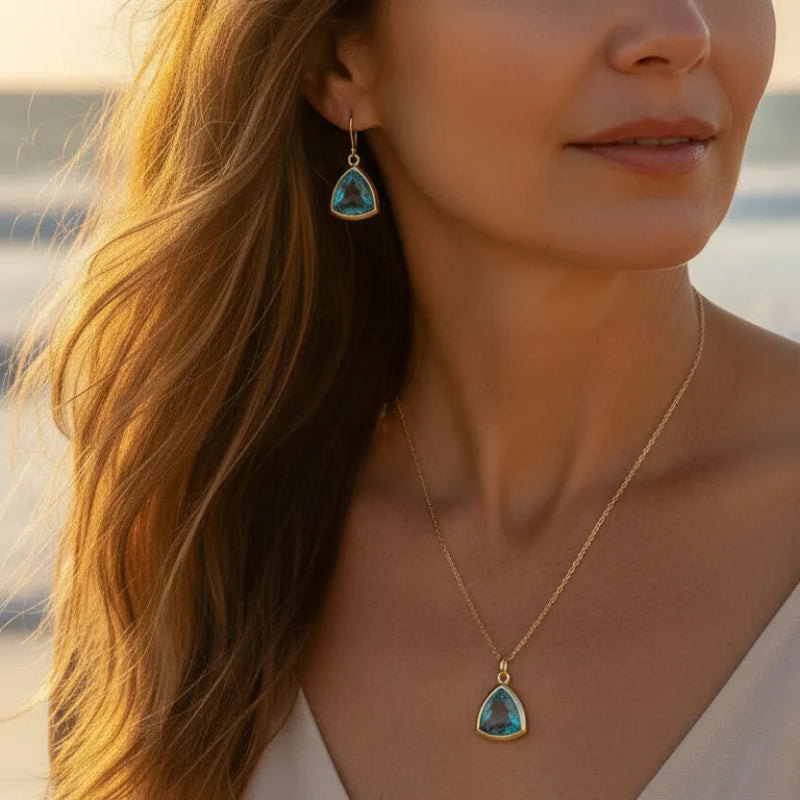 Woman wearing aqua Athena necklace and earrings in gold, March birthstone jewelry