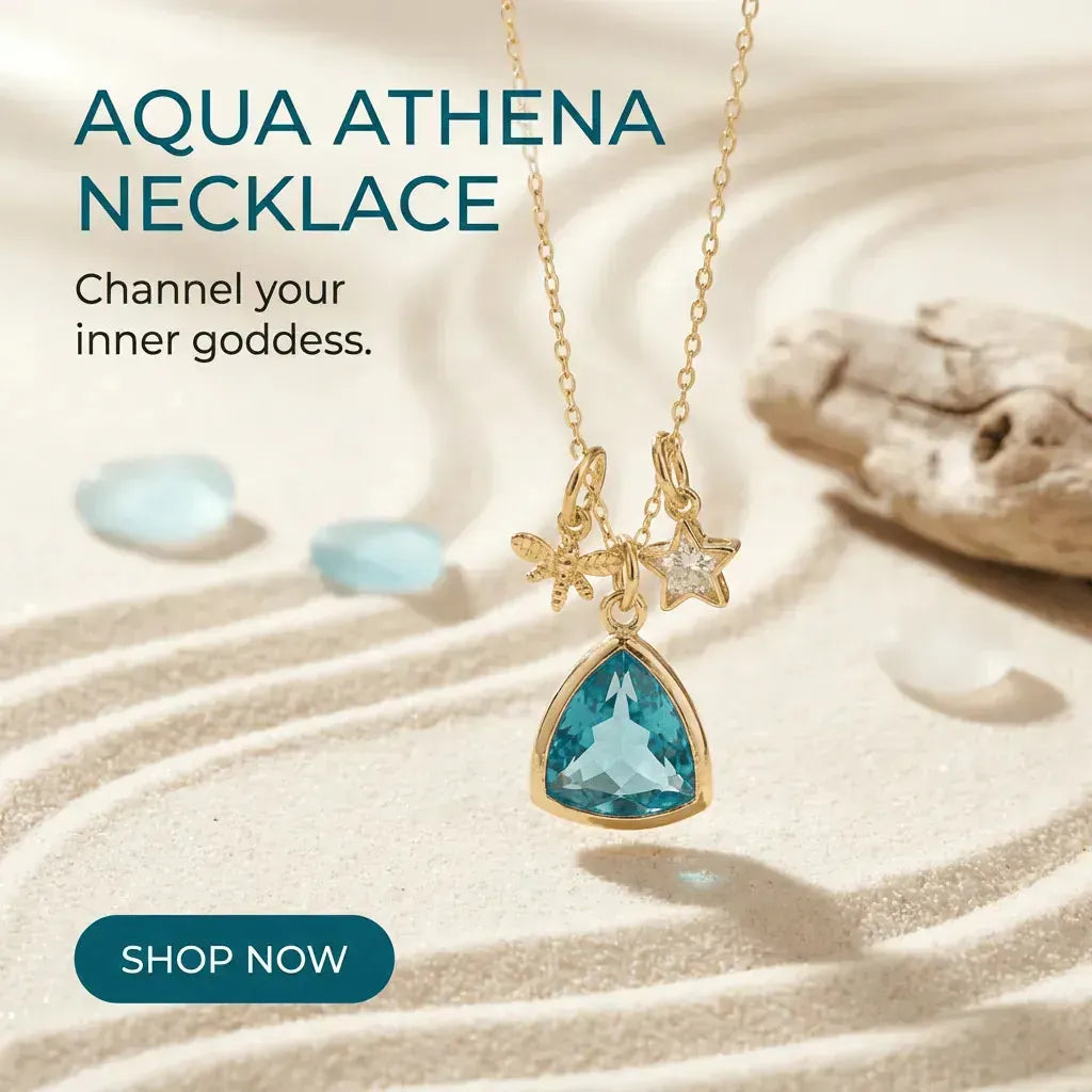 Aqua Athena necklace with blue gemstone and gold chain on sand background
