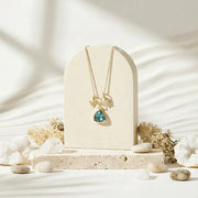 Necklace with a blue pendant on a beige stand with a natural stone and coral background
