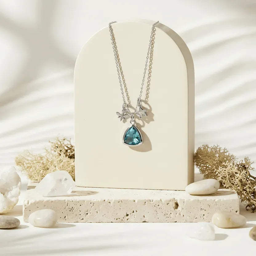 Necklace with a blue pendant on a white stand with a natural background